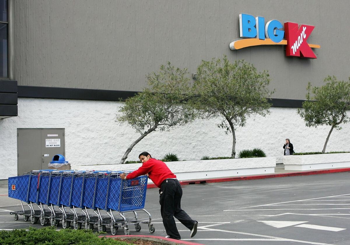 A worker pushes shopping carts through the parking lot of a Kmart store in San Mateo in 2005. The store is one of several the chain is closing.