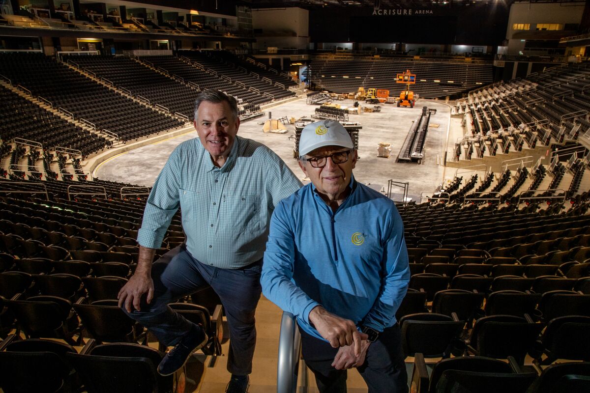 Two men pose inside an arena.