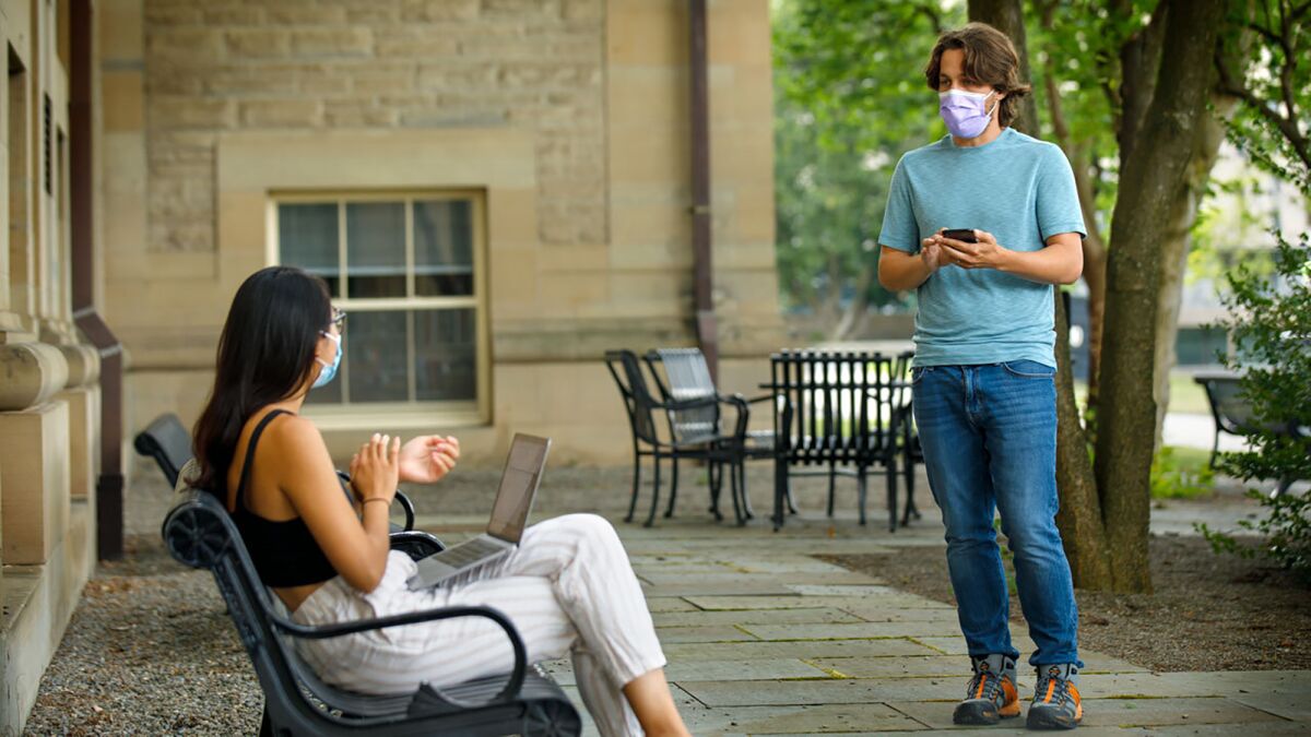 In this photo provided by Jason Koski and Cornell University, Bryan Maley, right, a grad student in the Master of Public Health program, interviews a student on campus about mask-wearing experiences as part of a public health survey, Friday, July 30, 2020, in Ithaca, N.Y. (Jason Koski/Cornell University via AP)