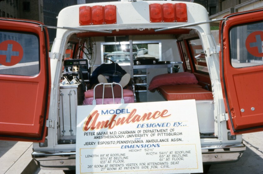 A model ambulance with its rear doors open and a sign describing its design