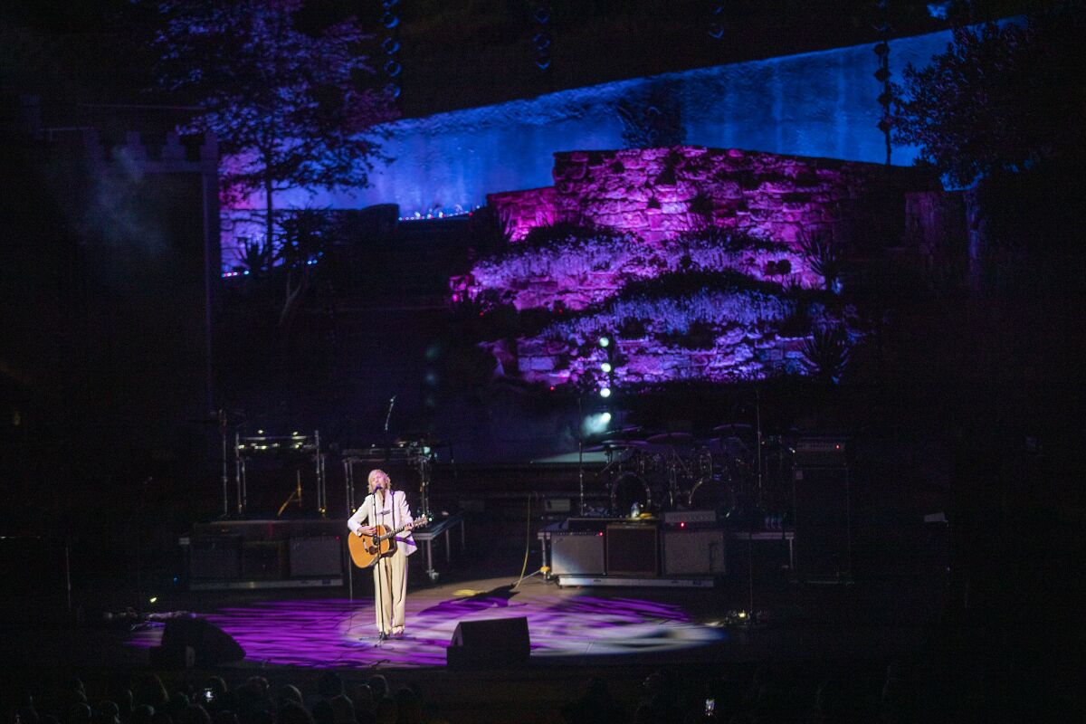 Beck plays his guitar and sings.