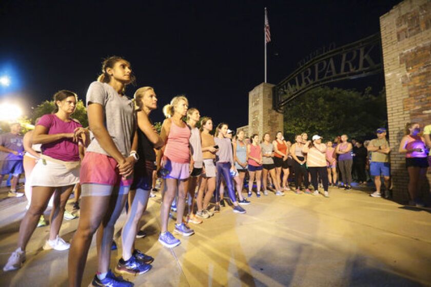 Members of the Tupelo Running Club and others gather for a moment of silence before they begin their "Liza's Lights" run early Friday morning, Spet. 9, 2022, in Tupelo Miss., to remember Eliza Fletcher, who was abducted and murdered while she was running in the early morning hours in Memphis, Tenn. (Thomas Wells/The Northeast Mississippi Daily Journal via AP)