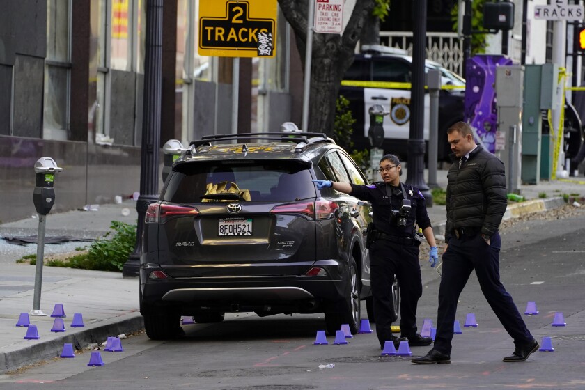 Two people are next to an SUV in a road with little purple cones on the ground.