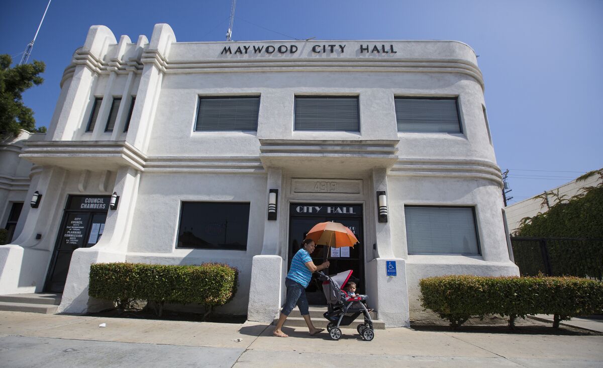 A woman pushes a toddler in a stroller past City Hall in Maywood.