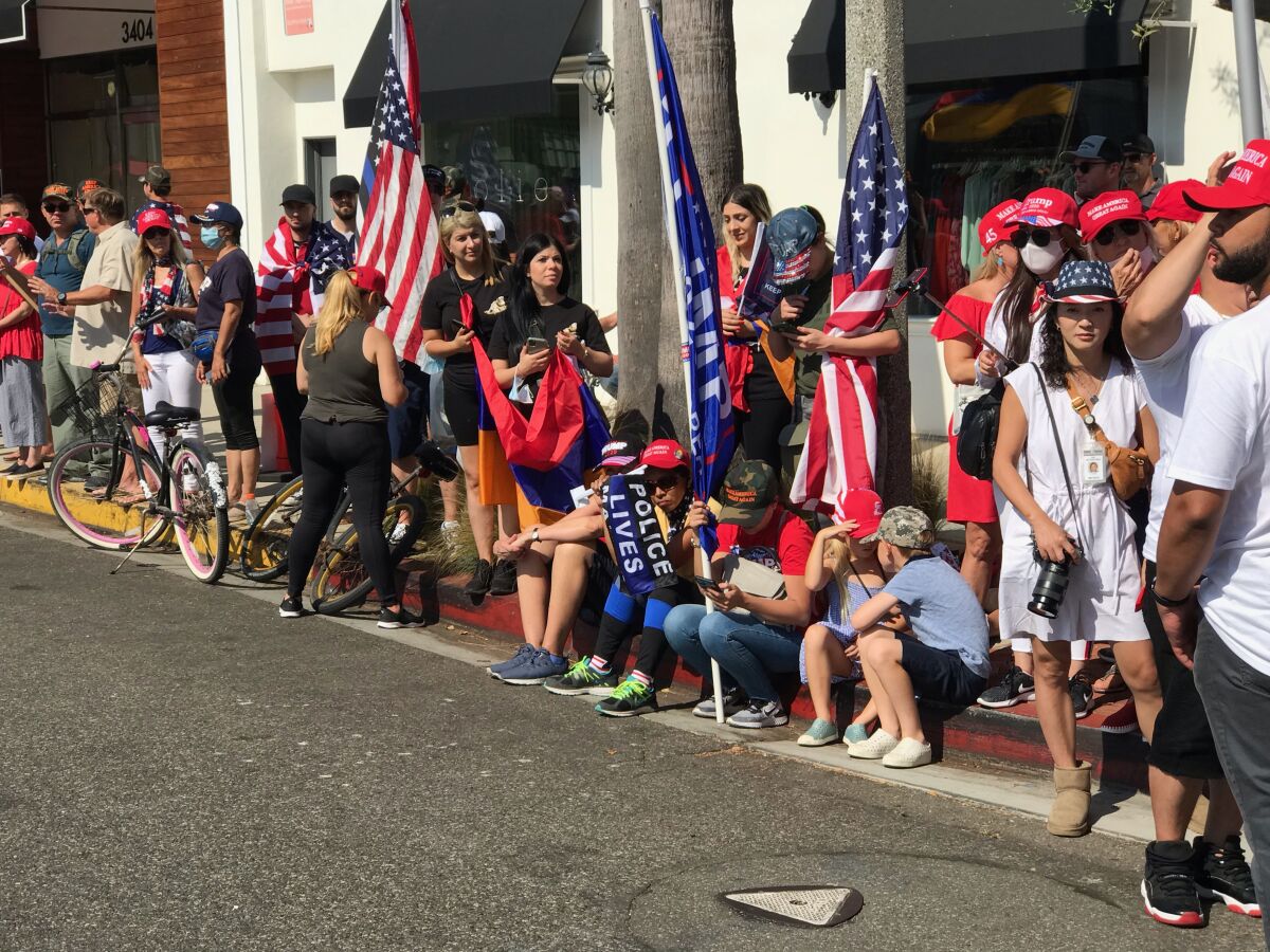 People with American flags and red hats gather along a street