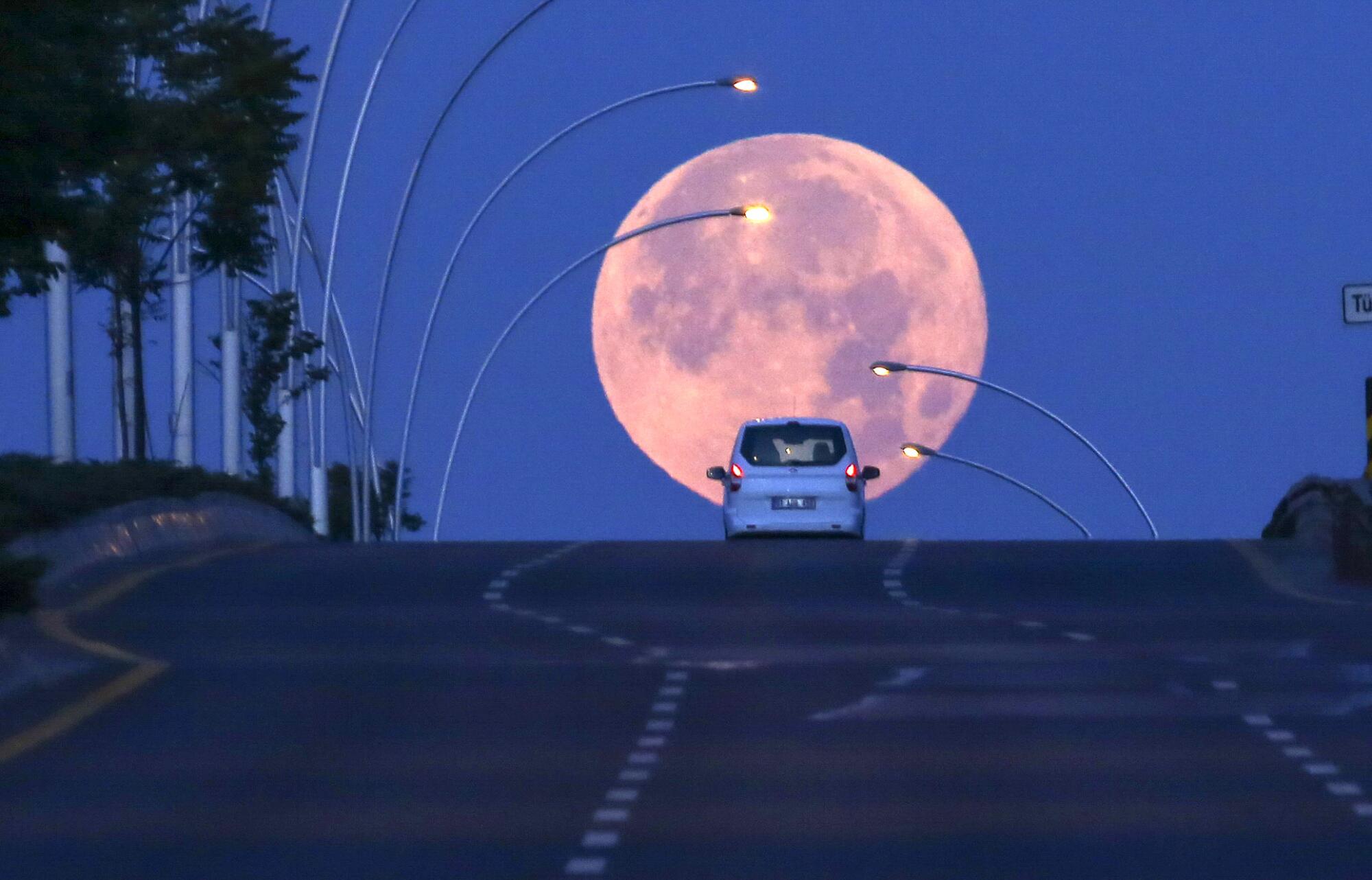 A vehicle in Ankara, Turkey, is silhouetted against the rising moon