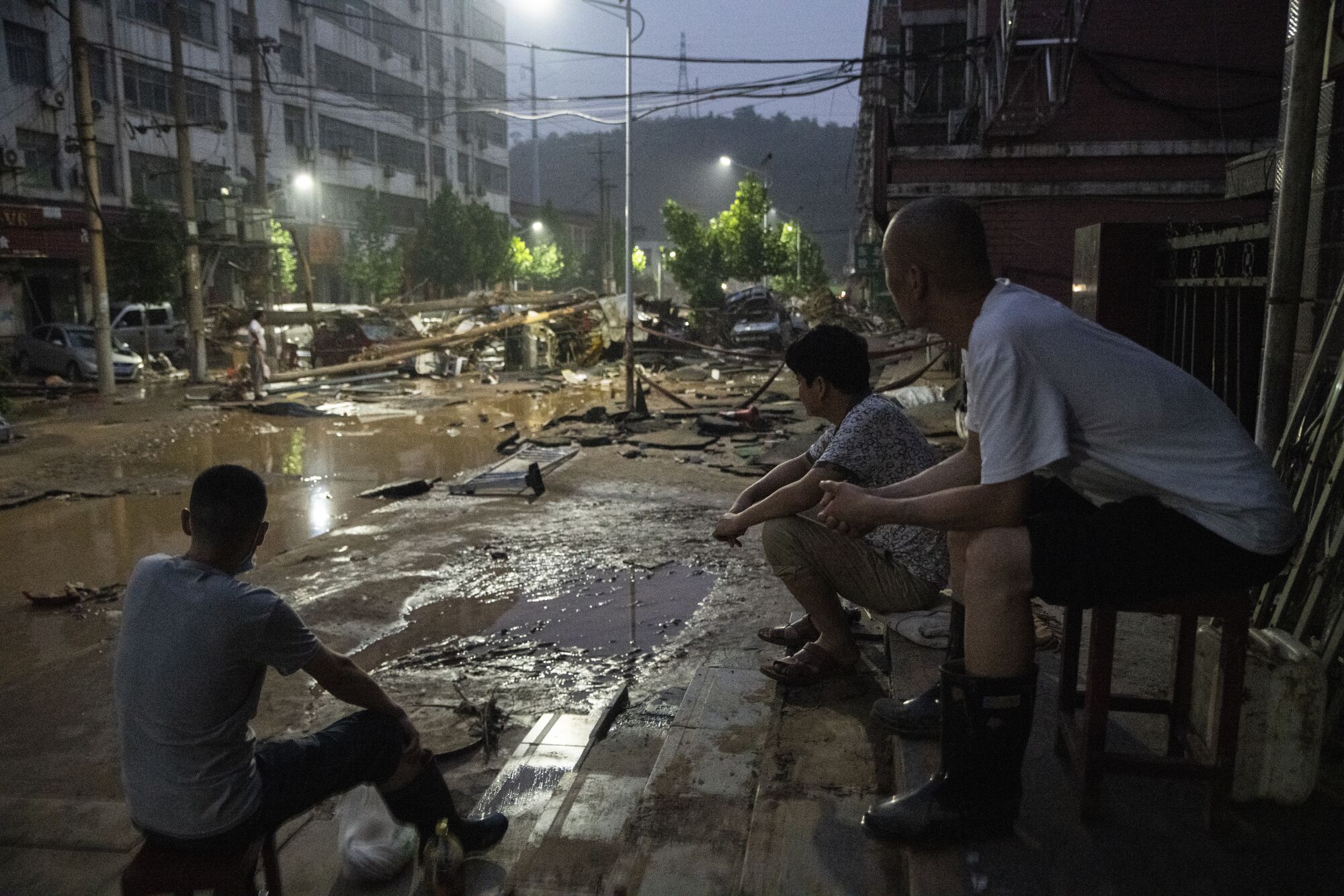 Three people view the flood damage from where they are sitting