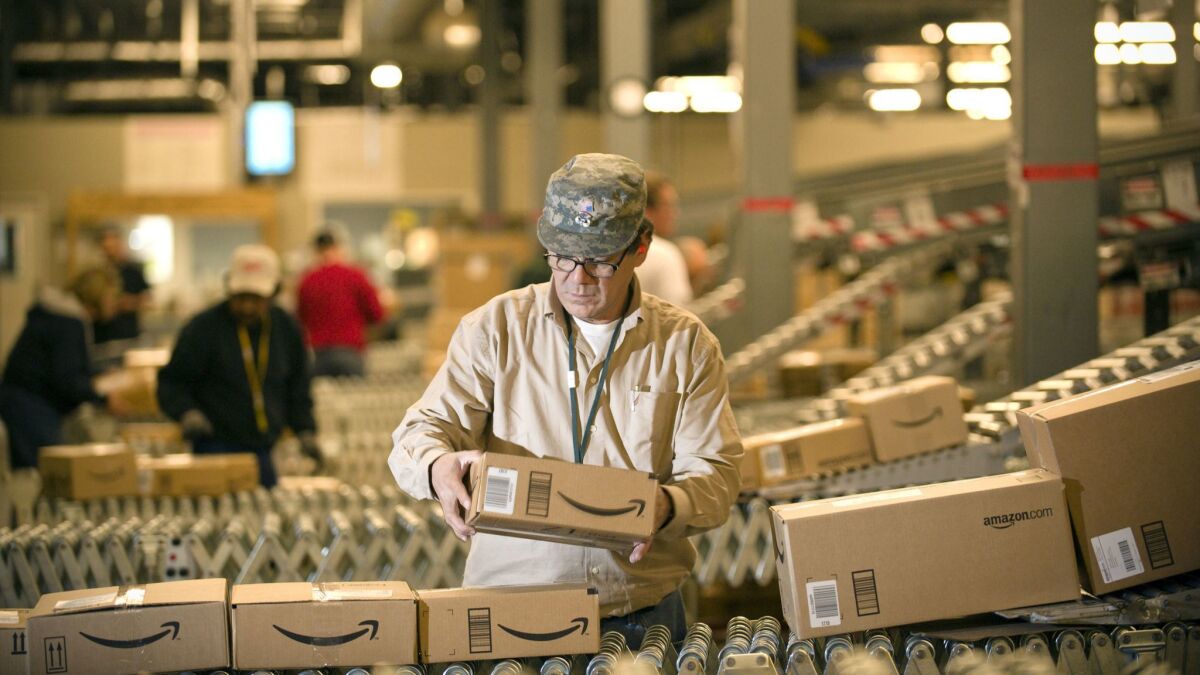 An Amazon.com employee grabs boxes off a conveyor belt at a Fernley, Nev., warehouse. "We have now less than half travel agents than before the internet boom," one academic said about automation. "Think if that happened to truck drivers and warehouse workers."