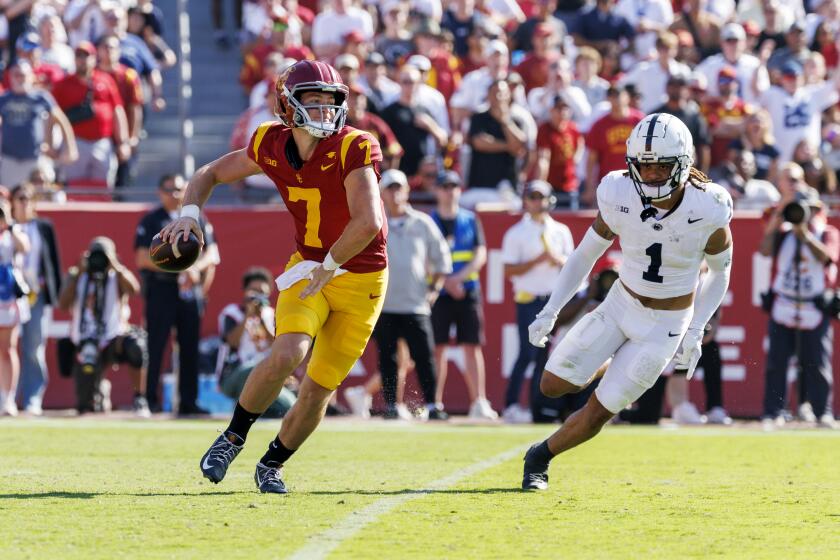 LOS ANGELES, CA - OCTOBER 12, 2024: USC Trojans quarterback Miller Moss (7) is forced to make a pass on the run with Penn State Nittany Lions safety Jaylen Reed (1) closing in at the LA Coliseum on October 12, 2024 in Los Angeles, California. (Gina Ferazzi / Los Angeles Times)