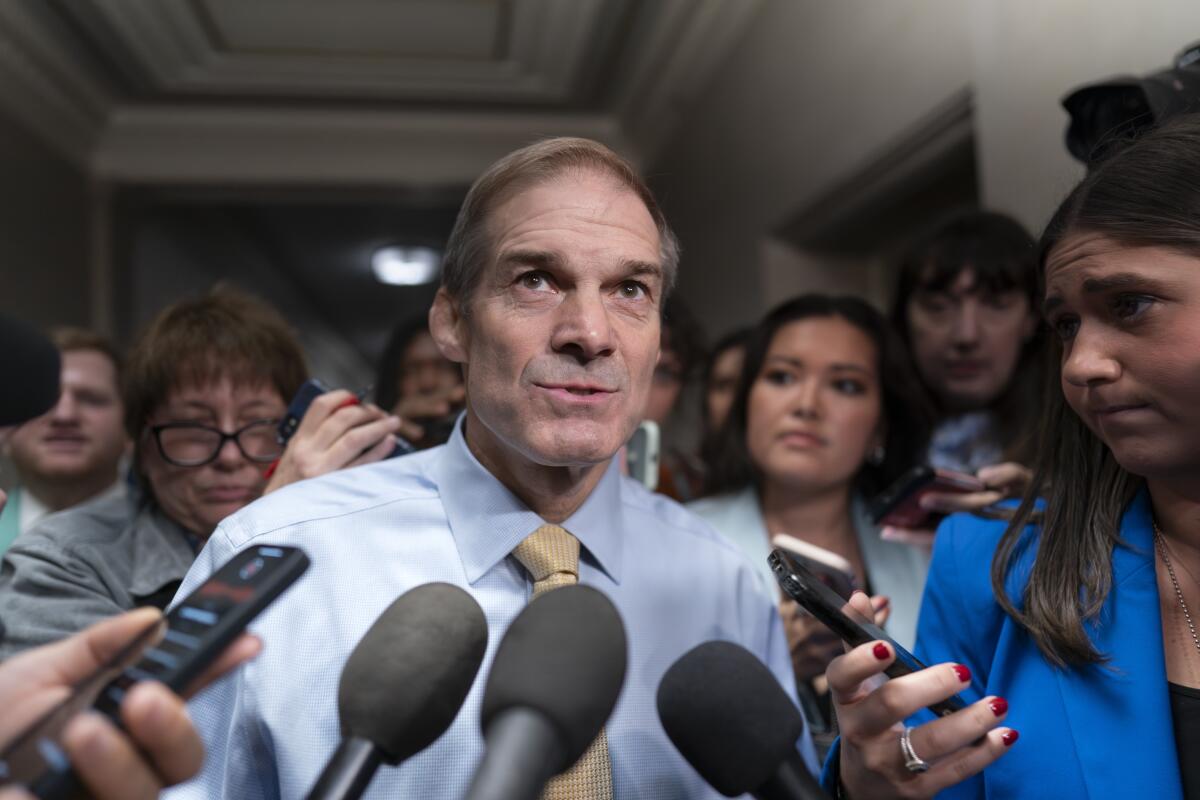 Rep. Jim Jordan of Ohio speakers into several microphones while surrounded by people.