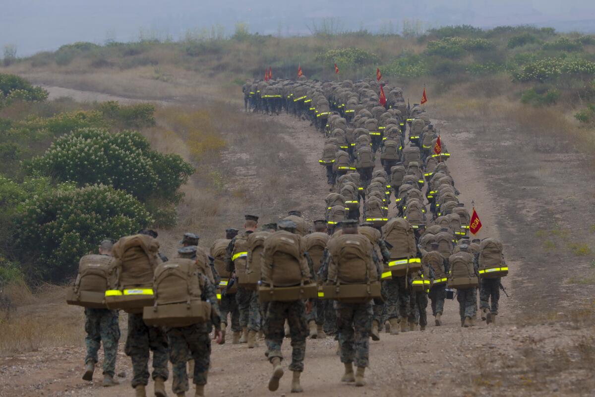 Marines walk up a hill.