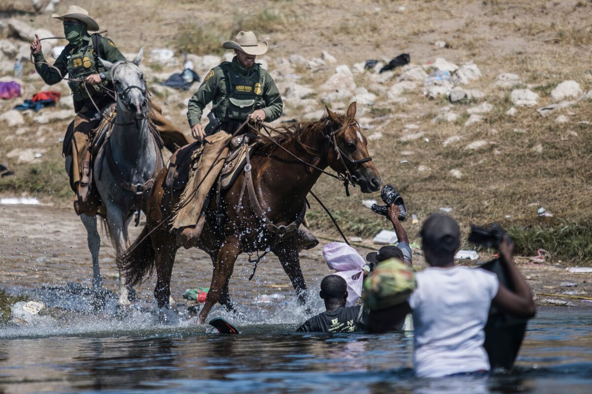 FILE - Mounted U.S. Border Patrol agents attempt to contain migrants as they cross the Rio Grande from Ciudad Acuña, Mexico, into Del Rio, Texas, Sept. 19, 2021. Border Patrol agents on horseback engaged in "unnecessary use of force" against non-threatening Haitian immigrants but didn't whip any with their reins, according to a federal investigation of chaotic scenes along the Texas-Mexico border last fall. (AP Photo/Felix Marquez, File)