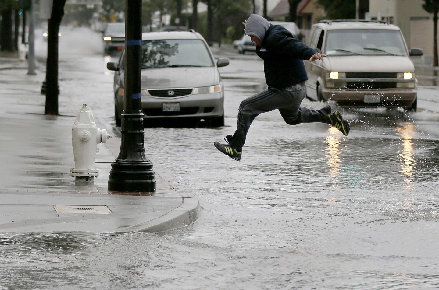 A pedestrian takes to flight crossing 4th Street in Santa Ana after heavy rain flooded the area.