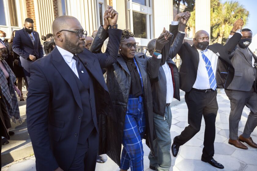 Ahmaud Arbery's mother Wanda Cooper-Jones, center, walks out of the Glynn County Courthouse surrounded by supporters after a judge sentenced Greg McMichael, his son, Travis McMichael, and a neighbor, William "Roddie" Bryan to life in prison, Friday, Jan. 7, 2022, in Brunswick, Ga. The three white men who chased and killed Ahmaud Arbery were sentenced Friday to life in prison, with a judge denying any chance of parole for the father and son who armed themselves and initiated the deadly permute of the 25-year-old Black man. (AP Photo/Stephen B. Morton)
