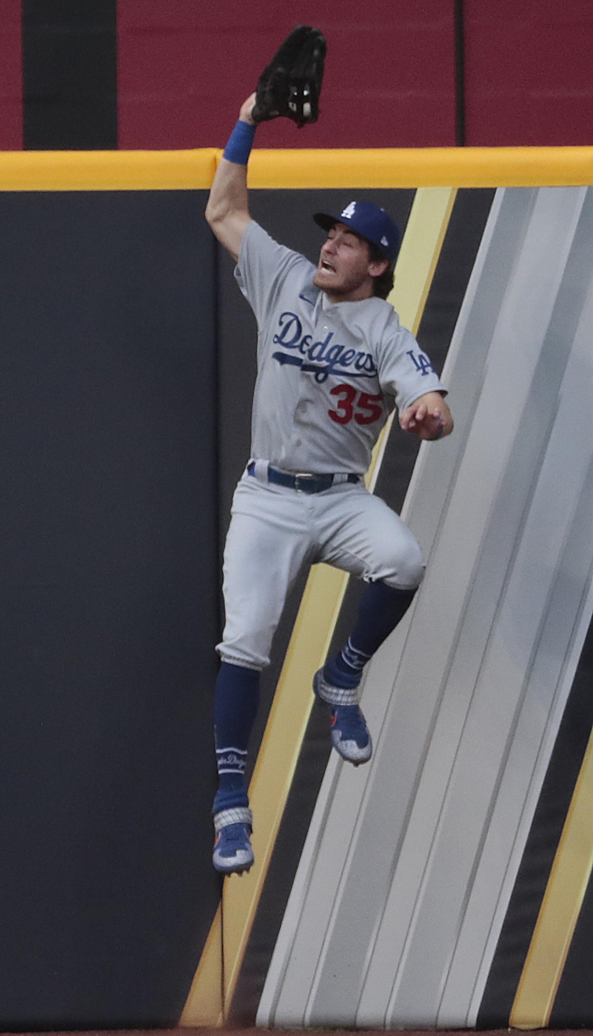 Dodgers center fielder Cody Bellinger leaps to catch a long fly at the wall.