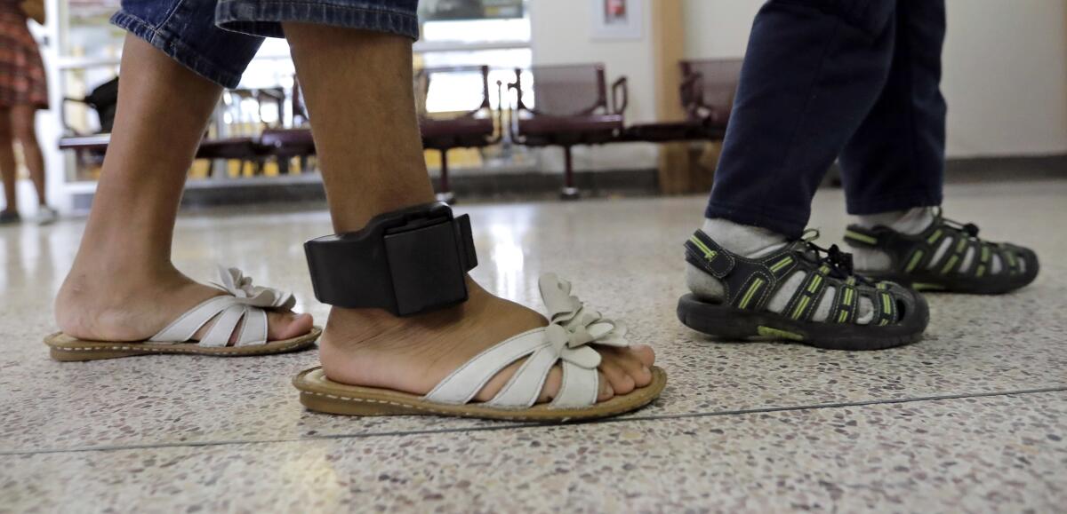 A woman's legs, with an ankle monitor on one ankle