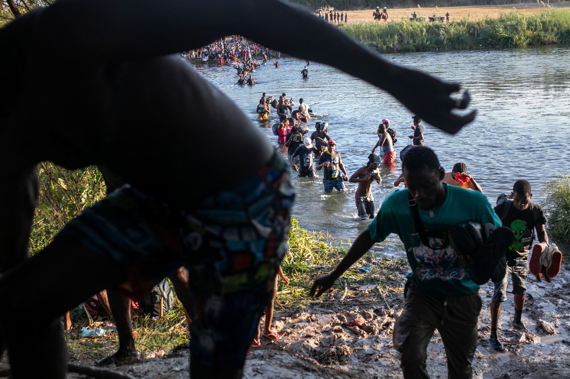 A long line of Haitian immigrants emerges from the banks of the Rio Grande and back onto Mexican soil.