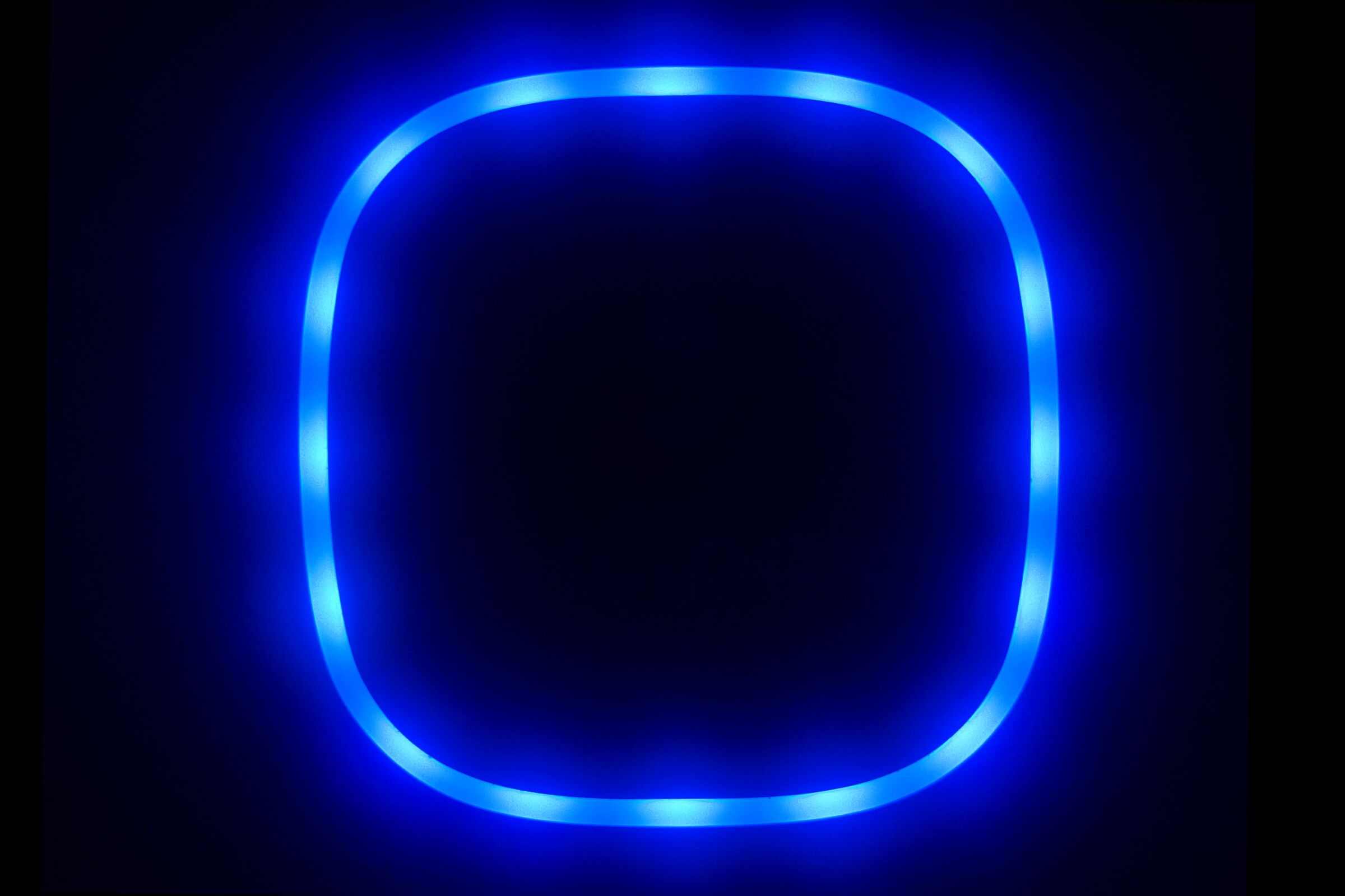 A glowing blue squared-off circle on the Wallbox home charger in a garage at night