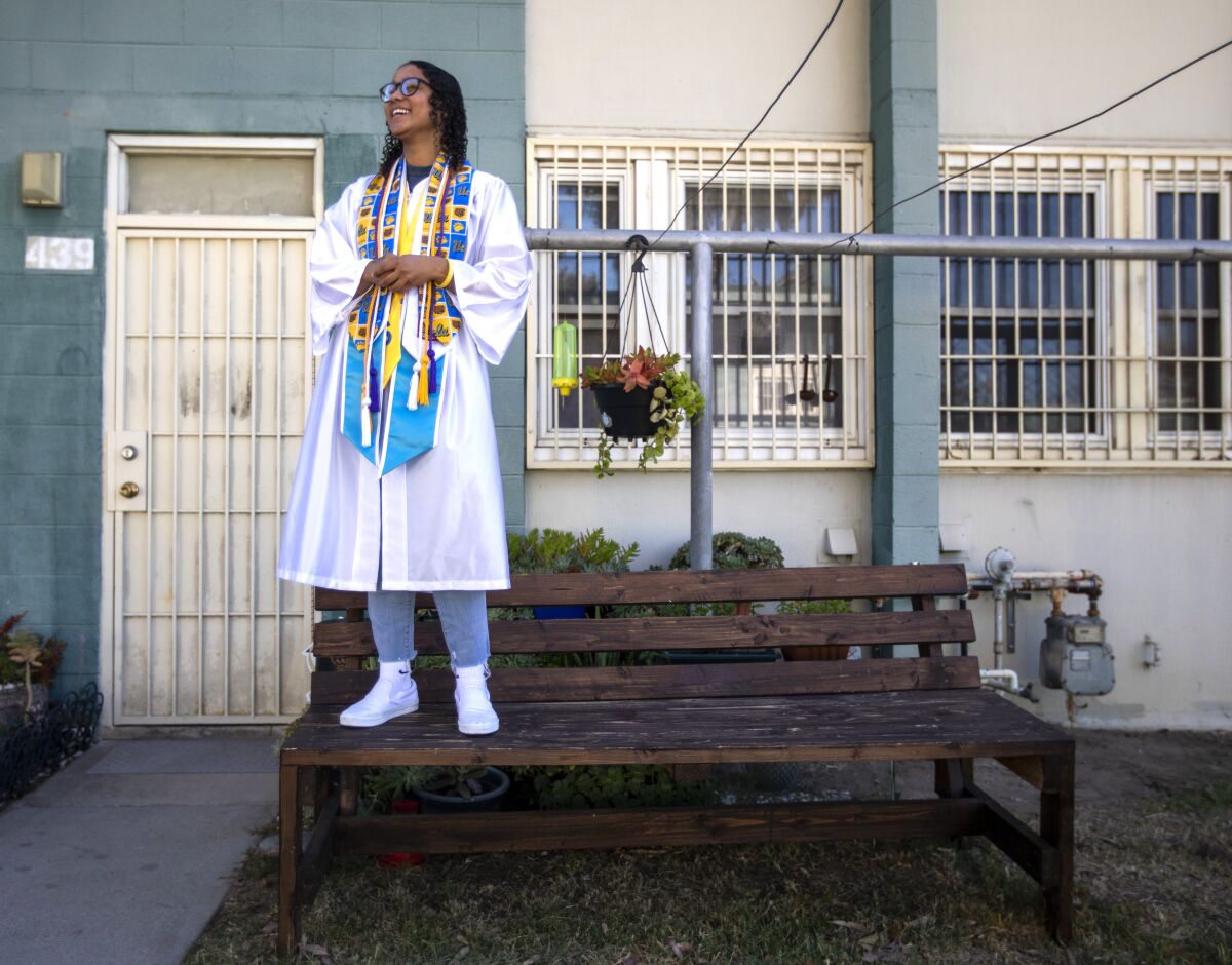 Pilar Diaz-Bombino stands on a bench in her graduation gown