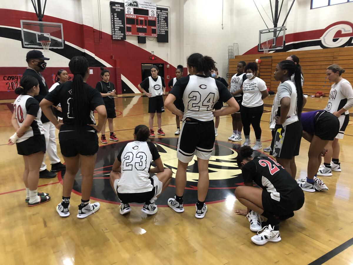 Corona Centennial girls' basketball players gather with coach Martin Woods for a meeting.