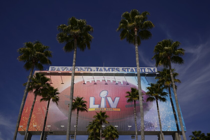 A sign for Super Bowl 55 is framed by palm trees at Raymond James Stadium Thursday, Feb. 4, 2021, in Tampa, Fla. The city is hosting Sunday's Super Bowl football game between the Tampa Bay Buccaneers and the Kansas City Chiefs. (AP Photo/Charlie Riedel)