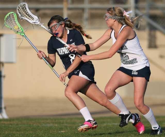 Corona del Mar's Tiffany Paladin, right, tries to steal the ball from Newport Harbor's Kristen Rohan during the Battle of the Bay lacrosse match at Newport Harbor High School on Friday.