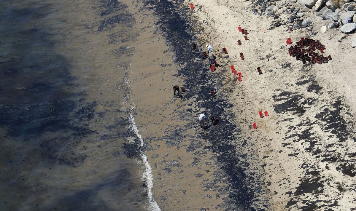 FILE - Volunteers fill buckets with oil near Refugio State Beach after an oil spill north of Goleta, Calif., May 20, 2015. A judge has approved a $230 million lawsuit settlement by the owners of a pipeline that spilled more than 140,000 gallons of crude oil into the ocean off California in 2015. (AP Photo/Michael A. Mariant, File)