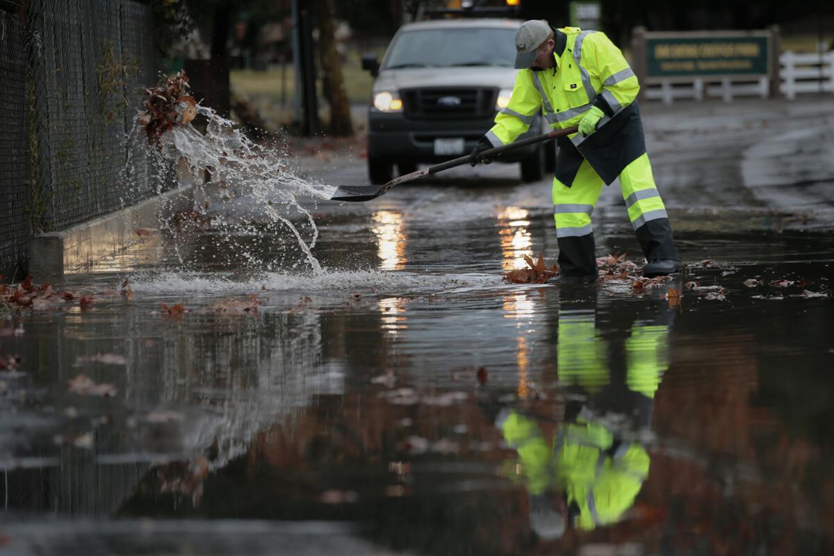 San Dimas Public Works Supervisor Terry Gregory clears a clogged drain in January as heavy rains caused flooding and mud flows in San Dimas, Glendora and Azusa.