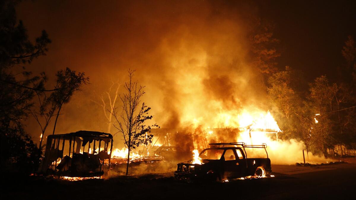 A car burns in front of a burning home in the Valley fire on Sept. 13, 2015, in Middletown, Calif.