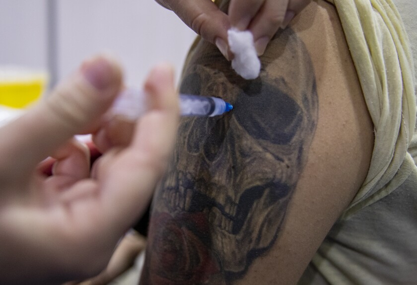 Una trabajadora de salud le inyecta a un estudiante una dosis de la vacuna CanSino contra el COVID-19 