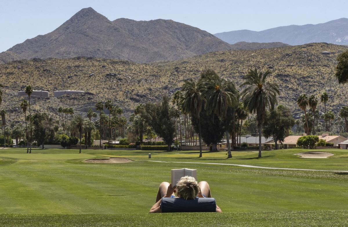 A Palm Springs resident reads at the Tahquitz Creek Golf Resort, which has been closed to players.