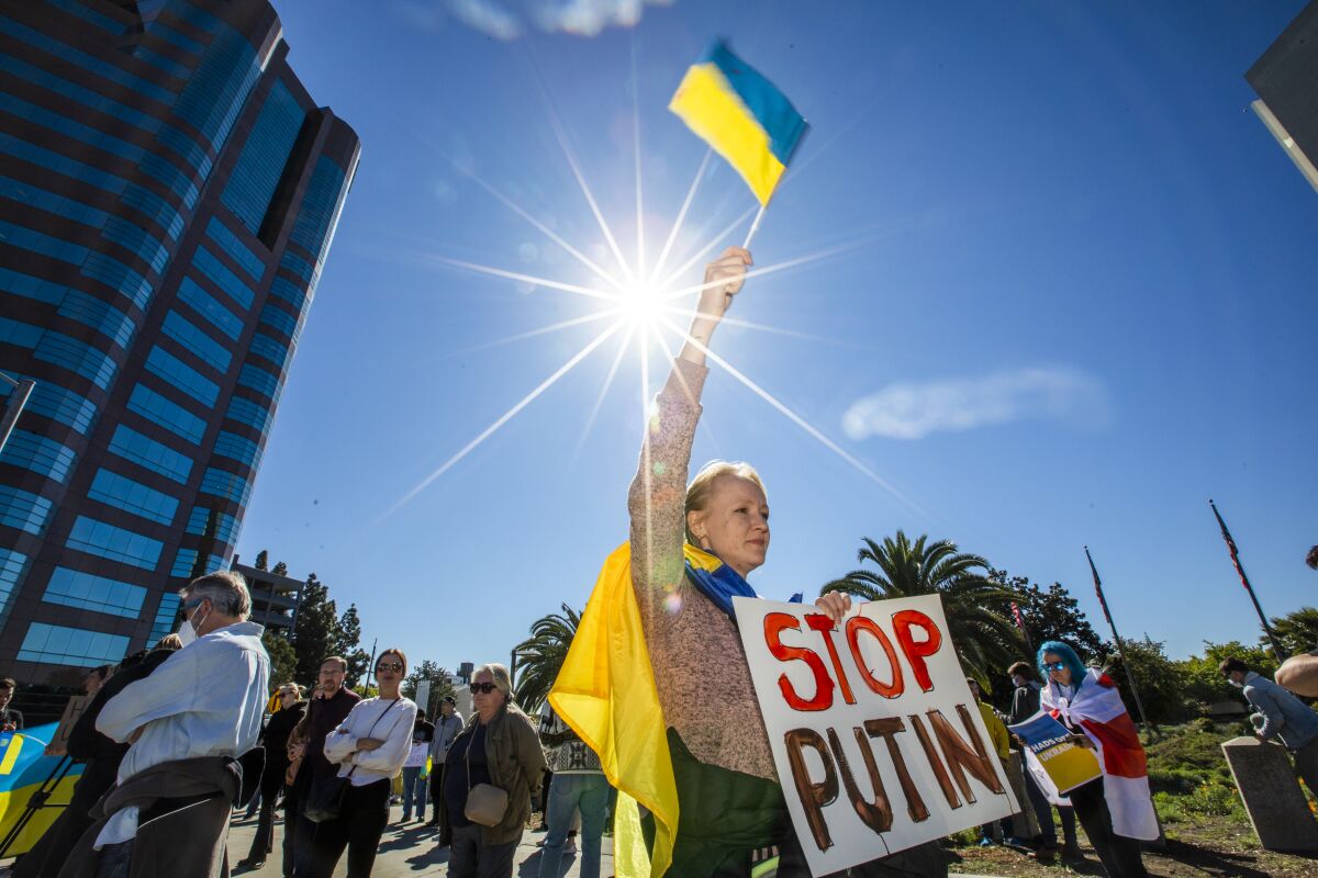 A demonstrator in Westwood holds a Ukrainian flag and a "Stop Putin" sign.