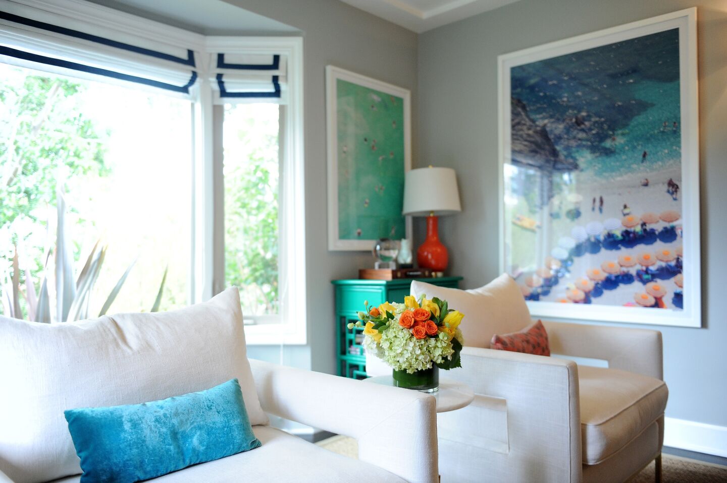Designer Orlando Soria from Home Polish helped Malin and Richardson decorate. In the living room, the white bordered window shades by Neal Bernardino and upholstered armchairs add sophistication to a room with bright splashes of color.