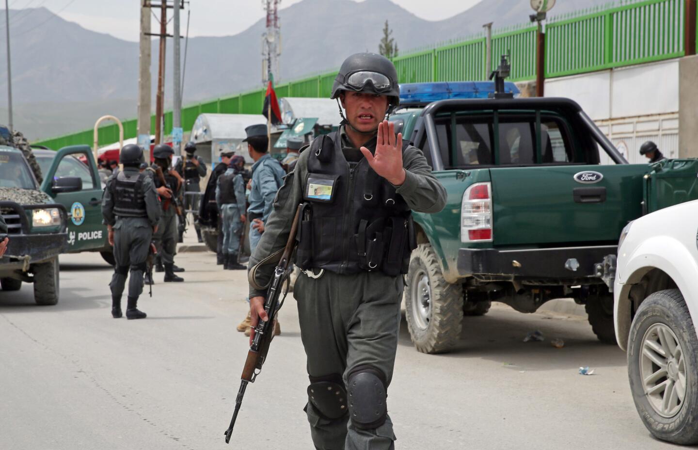 An Afghan policeman prevents journalists from approaching Cure International Hospital in Kabul, Afghanistan, on Thursday. The U.S. Embassy in Afghanistan says three American doctors have been killed by an Afghan security guard who opened fire at the hospital in Kabul.