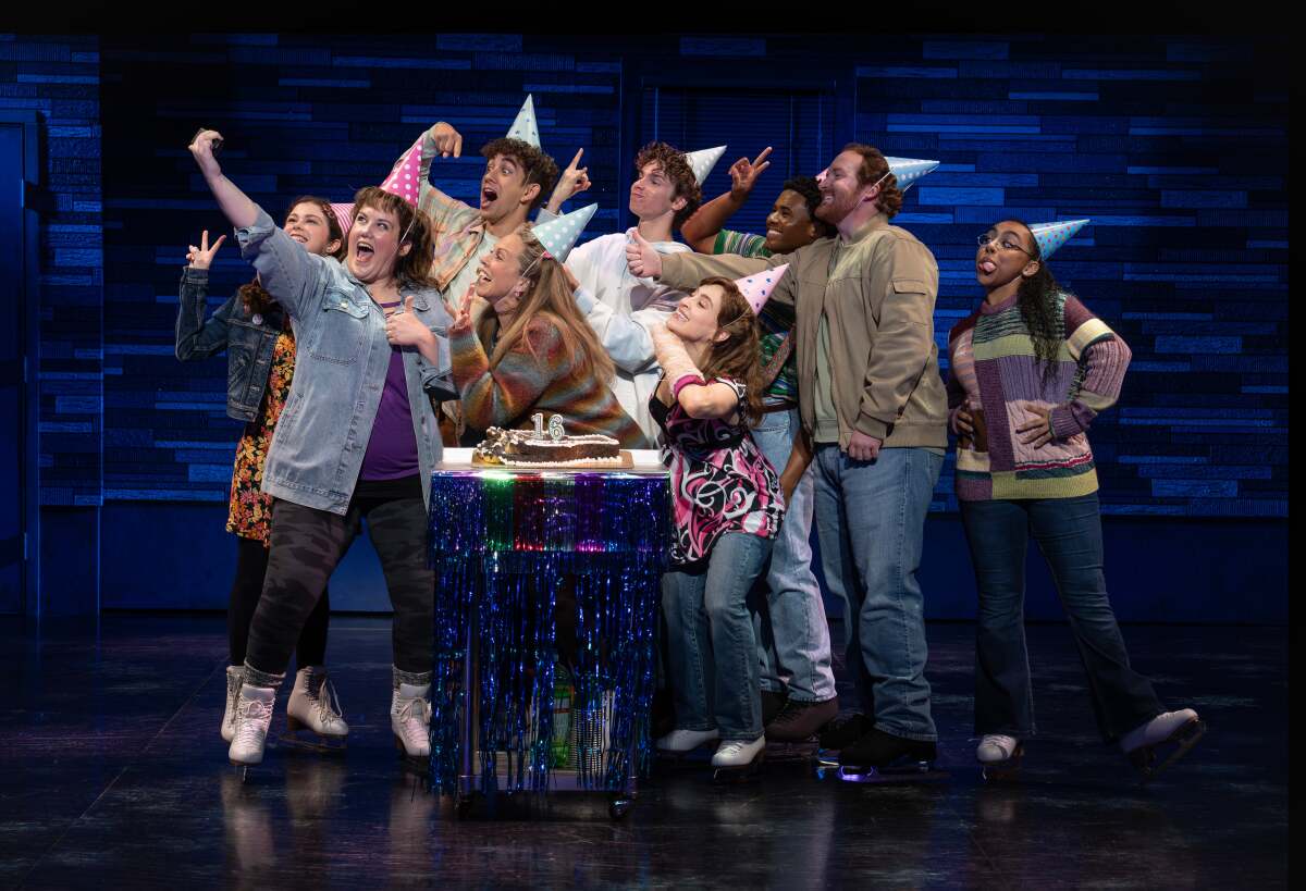 A group of people onstage pose for a selfie at a birthday party