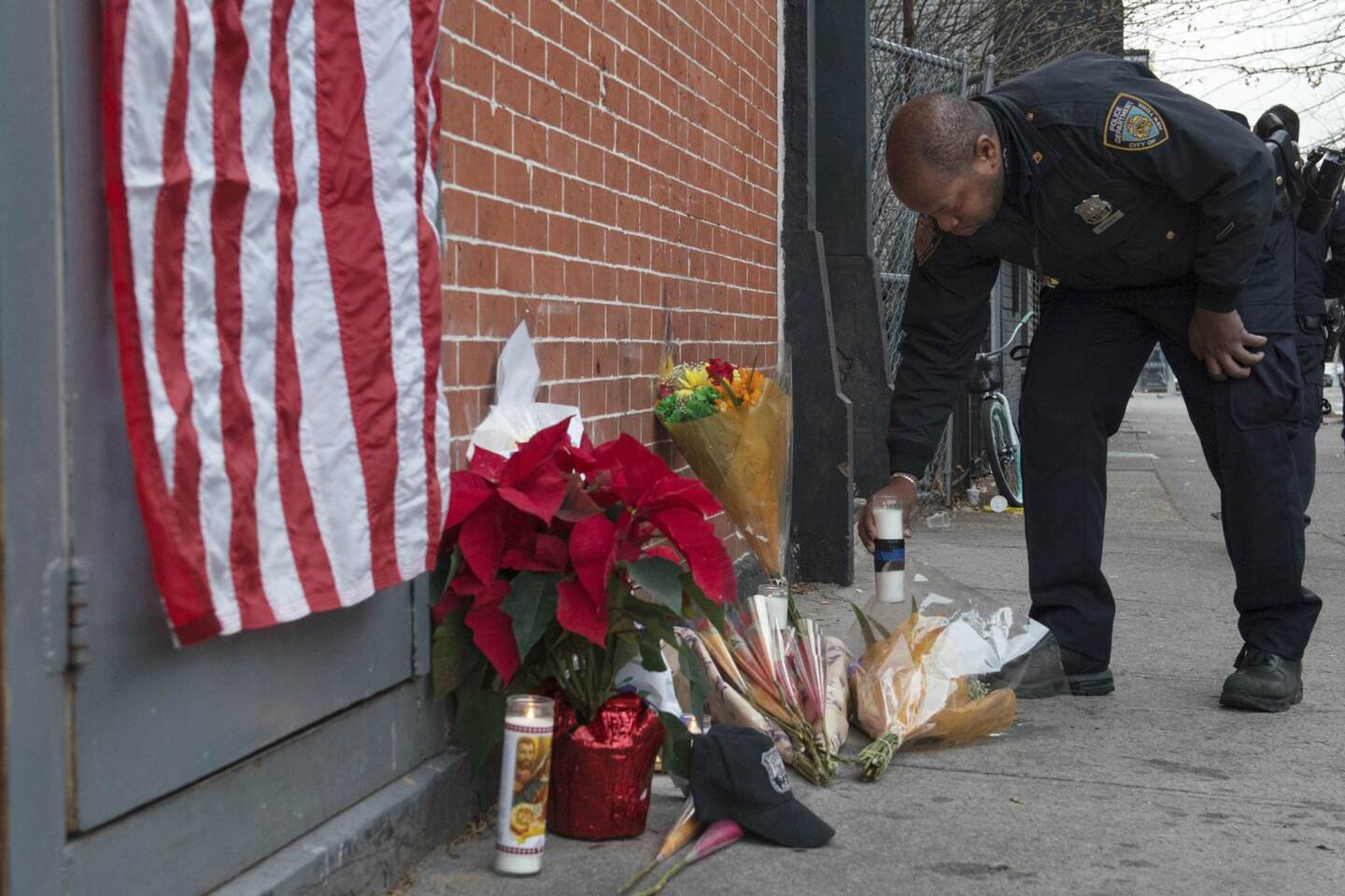 A police officer lays flowers at a makeshift memorial at the scene were two police officers were shot dead in the Brooklyn borough of New York