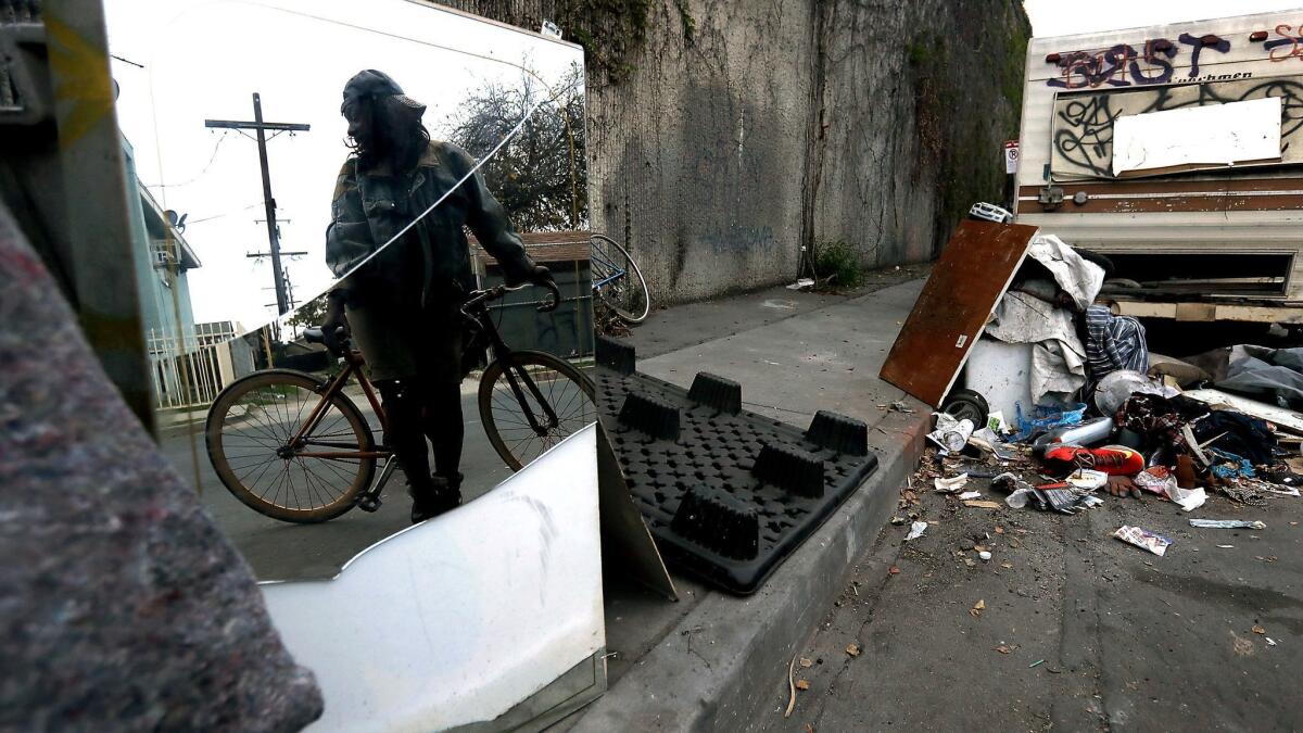 Homeless people live in tents, cars and recreational vehicles beside a wall that separates Grand Avenue and the Harbor Freeway in South L.A.