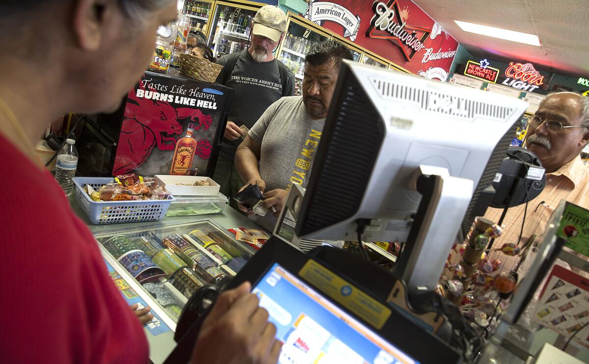 Clerk Ruby Sran, left, helps customers purchase Mega Millions lottery tickets at Allan's Market Wine and Lotto in Port Hueneme on Wednesday.