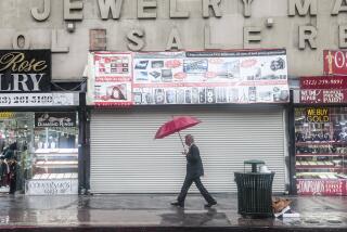 Los Angeles, CA - August 20: A person walks under an umbrella during Tropical Storm Hilary while downtown on Sunday, Aug. 20, 2023 in Los Angeles, CA. Southern California is under a first-ever tropical storm warning as Hilary approaches with parts of California, Arizona, and Nevada preparing for flooding and heavy rains. (Dania Maxwell / Los Angeles Times)