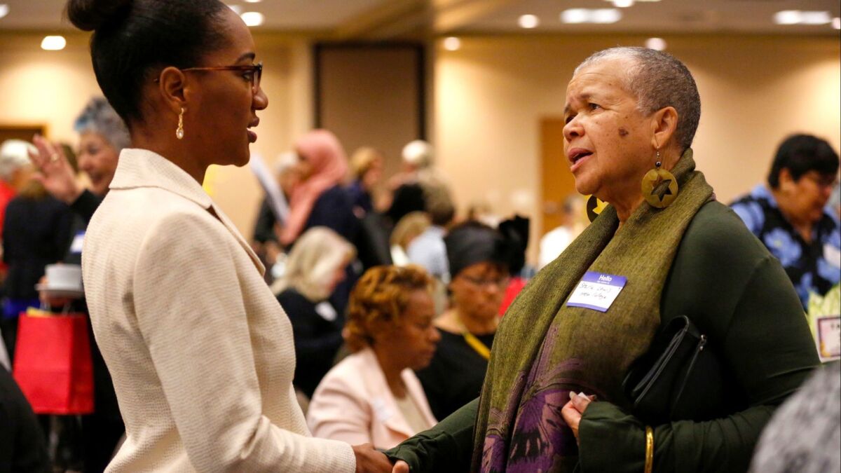 Nasheema Harvey, left, meets poet/author Starla Lewis prior to the start of the Indivisible WATU Women of Color ROAR breakfast at the Jacobs Center for Neighborhood Innovation on Saturday morning.