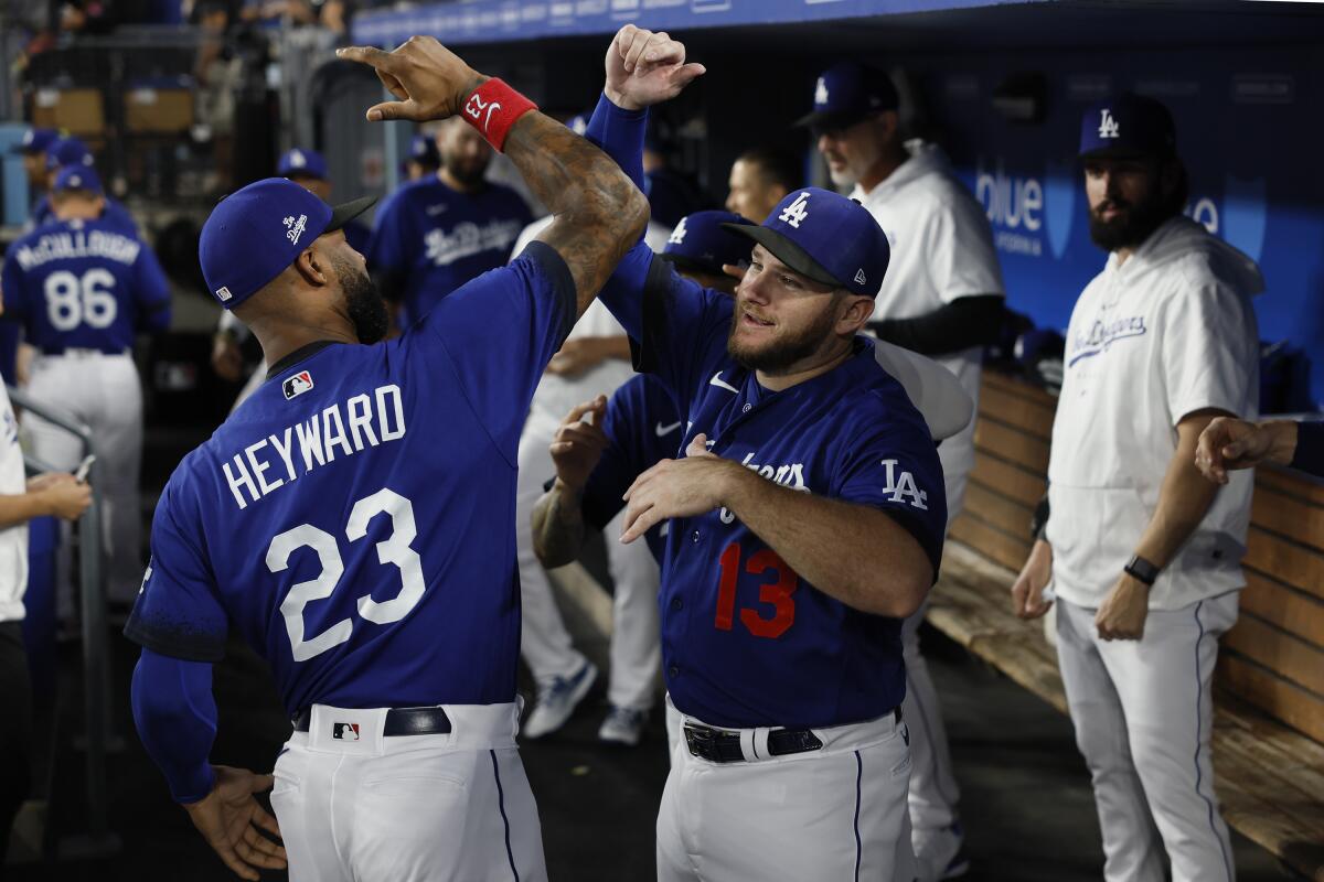 Dodgers teammates Jason Heyward and Max Muncy greet one another in the dugout.