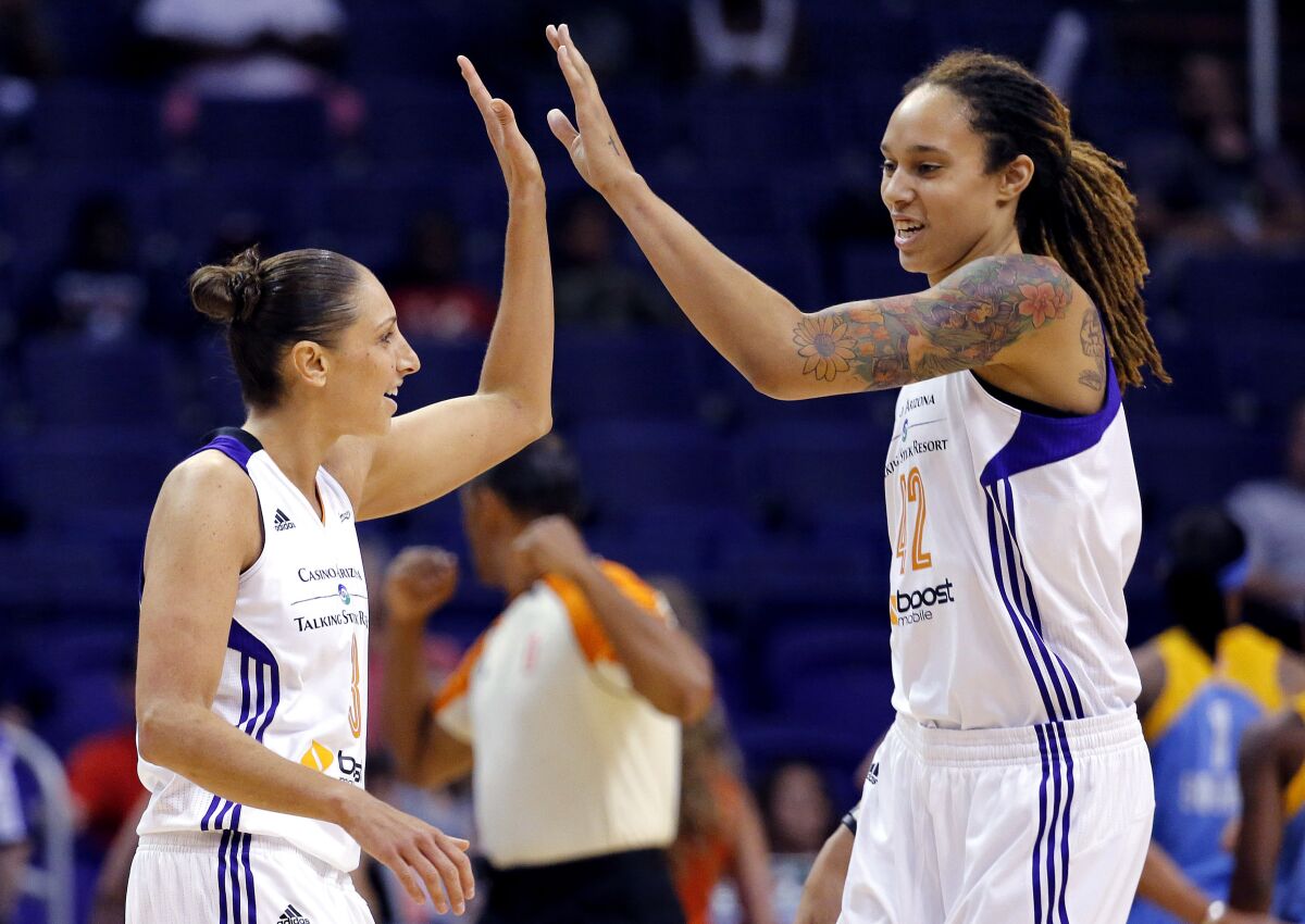 FILE - Phoenix Mercury guard Diana Taurasi, left, high-fives teammate Brittney Griner during the first half of a WNBA basketball game against the Chicago Sky, on July 2, 2014, in Phoenix. Griner texted her good friend Diana Taurasi on Tuesday morning, Feb. 7, 2023, asking how the USA Basketball training camp was going. Griner was back in Arizona, choosing to skip the camp in Minnesota so she can be with her wife and recover from her time in a Russian jail. She returned to the U.S. in December after a dramatic prisoner swap. (AP Photo/Matt York, File)