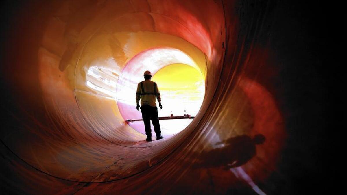 Un trabajador de la construcción instala sellador en uno de los toboganes de agua gigantes en el Great Wolf Lodge en Garden Grove en junio.