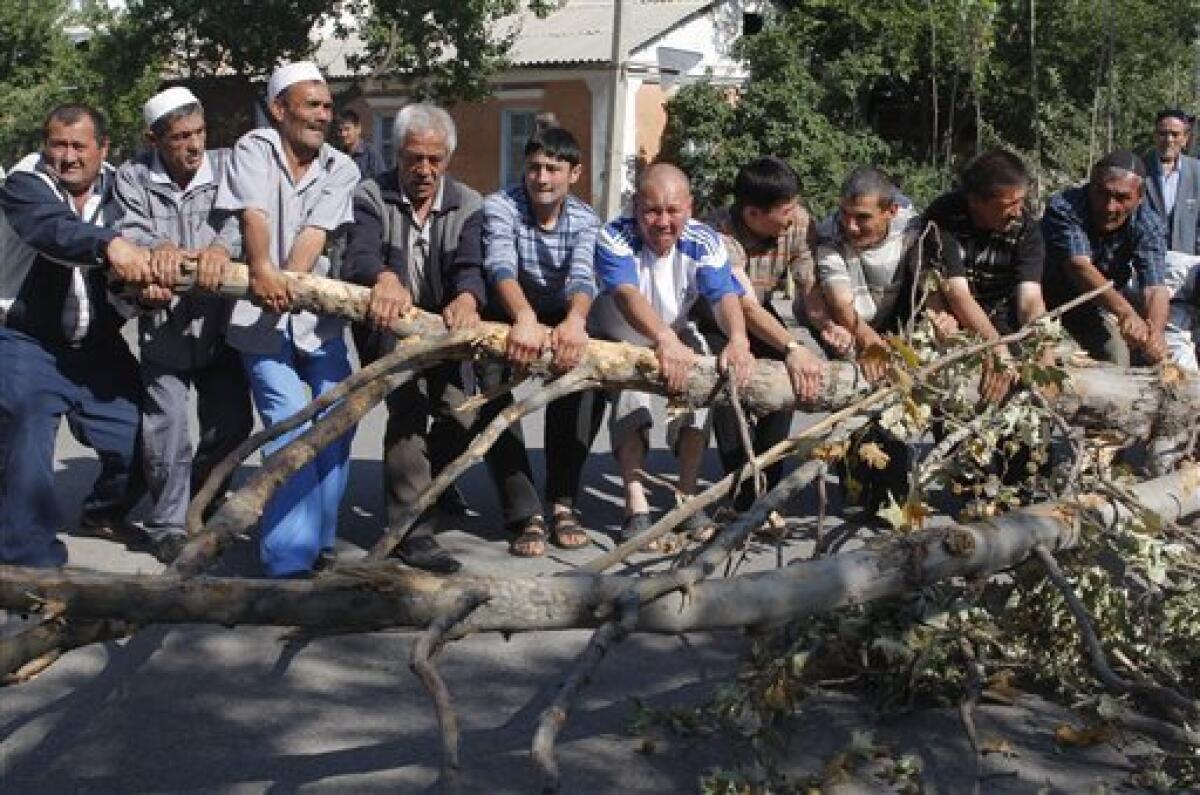 Ethnic Uzbeks and Kyrgyz jointly dismantle a street barricade on the border of Uzbek district in the southern city of Osh, Saturday, June 19, 2010. Some 4,500 refugees have returned to Kyrgyzstan from neighboring Uzbekistan in the past few days, the Kyrgyz Border Service said in its press release on Saturday, according to reports by Itar-Tass. (AP Photo/Sergei Grits)