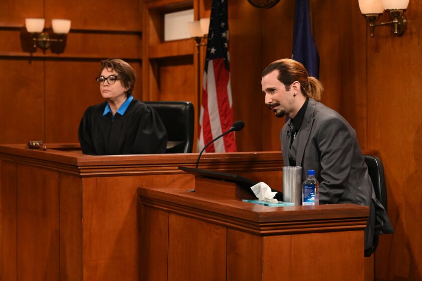 A woman dressed like a judge and a man dressed like Johnny Depp, seated in a court room