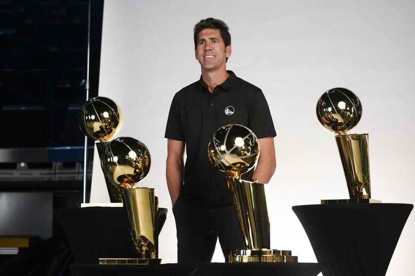 Golden State Warriors general manager Bob Myers poses next to four NBA championship trophies.