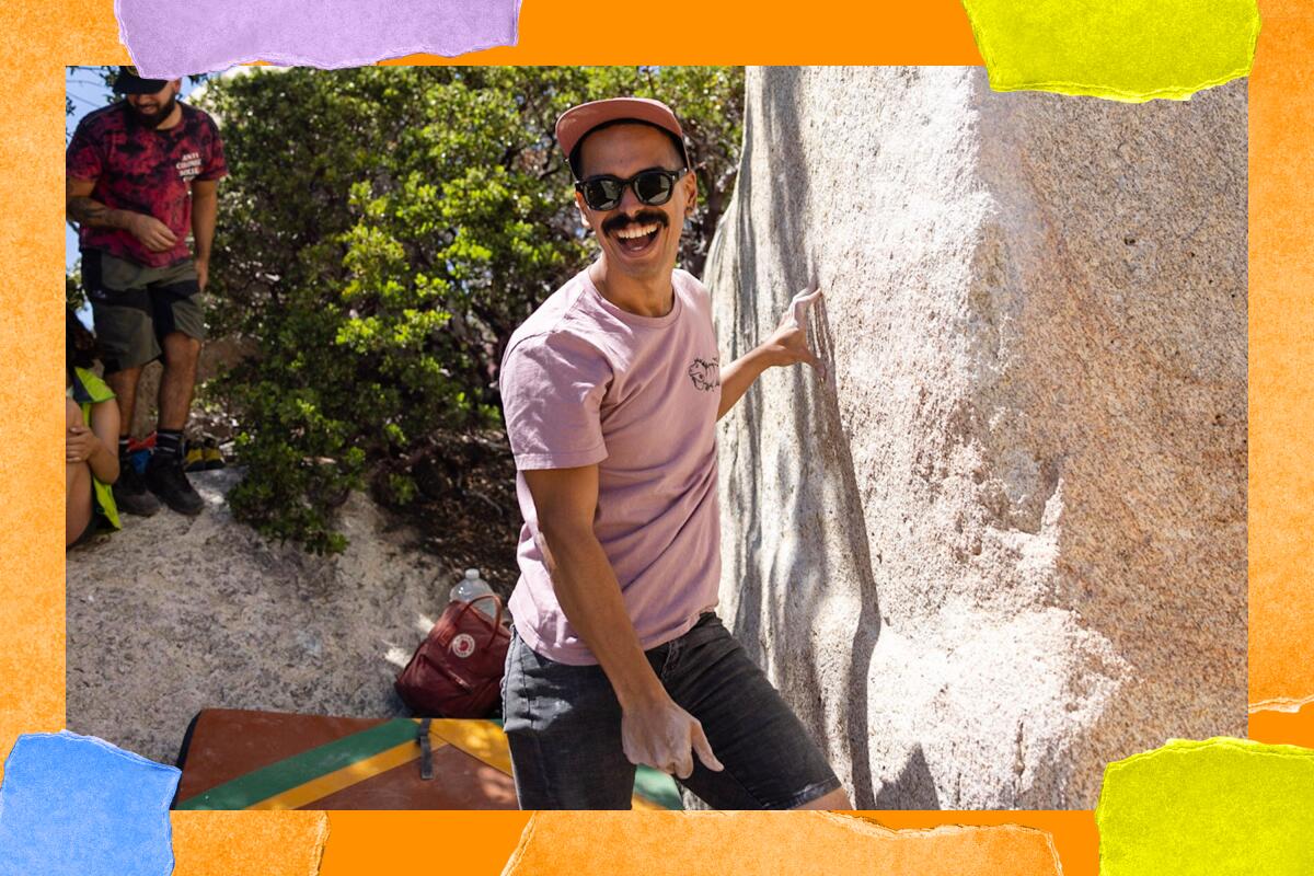 Anuardi Cantre-Santiago wears sunglasses and a pink shirt and stands next to a large rock.