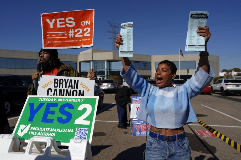 FILE - Nikko Griffin, left, and Tyra Patterson, call out to arriving voters for several issues, including Issue 2, legalizing recreational marijuana, at a parking lot during early in-person voting in Cincinnati, Nov. 2, 2023. (AP Photo/Carolyn Kaster, File)