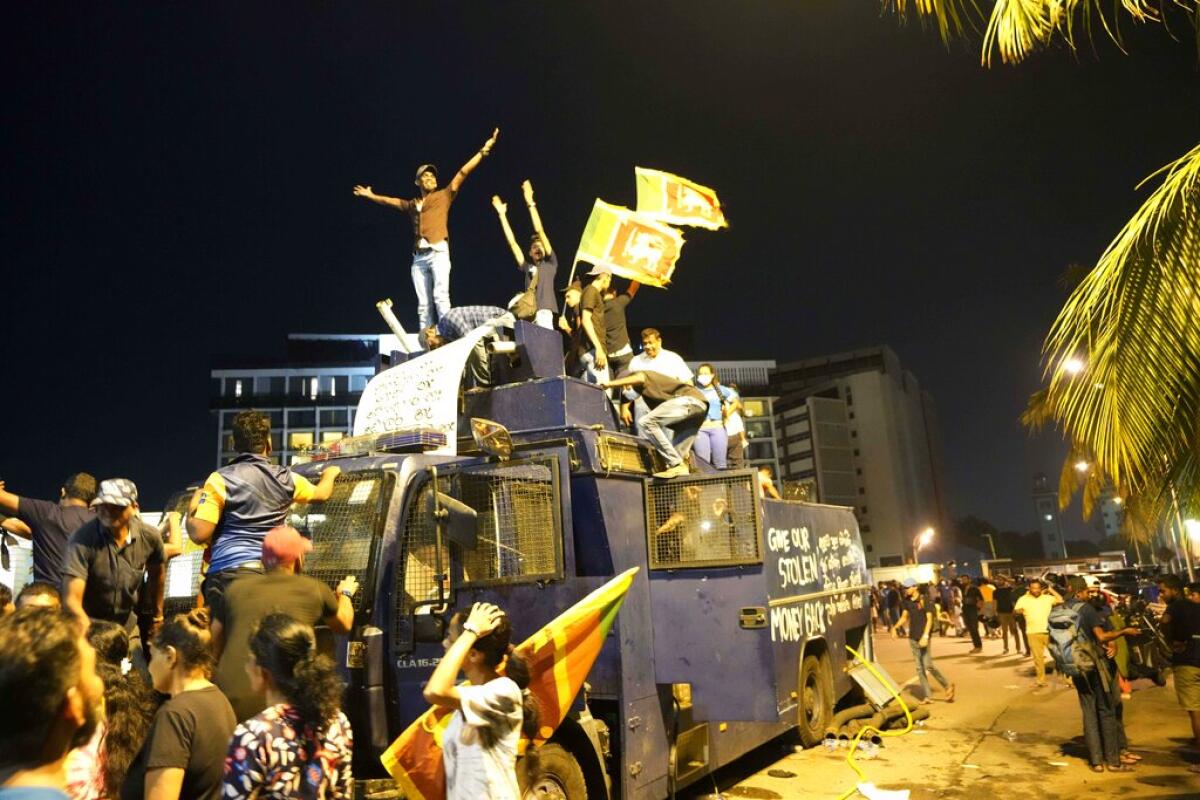 Manifestantes celebran sobre un camión vandalizado de la policía