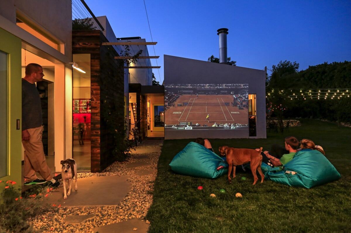 Movies (or, here, a tennis match) are an outdoor activity when projected onto an outside wall. For more on this house, read the related article.